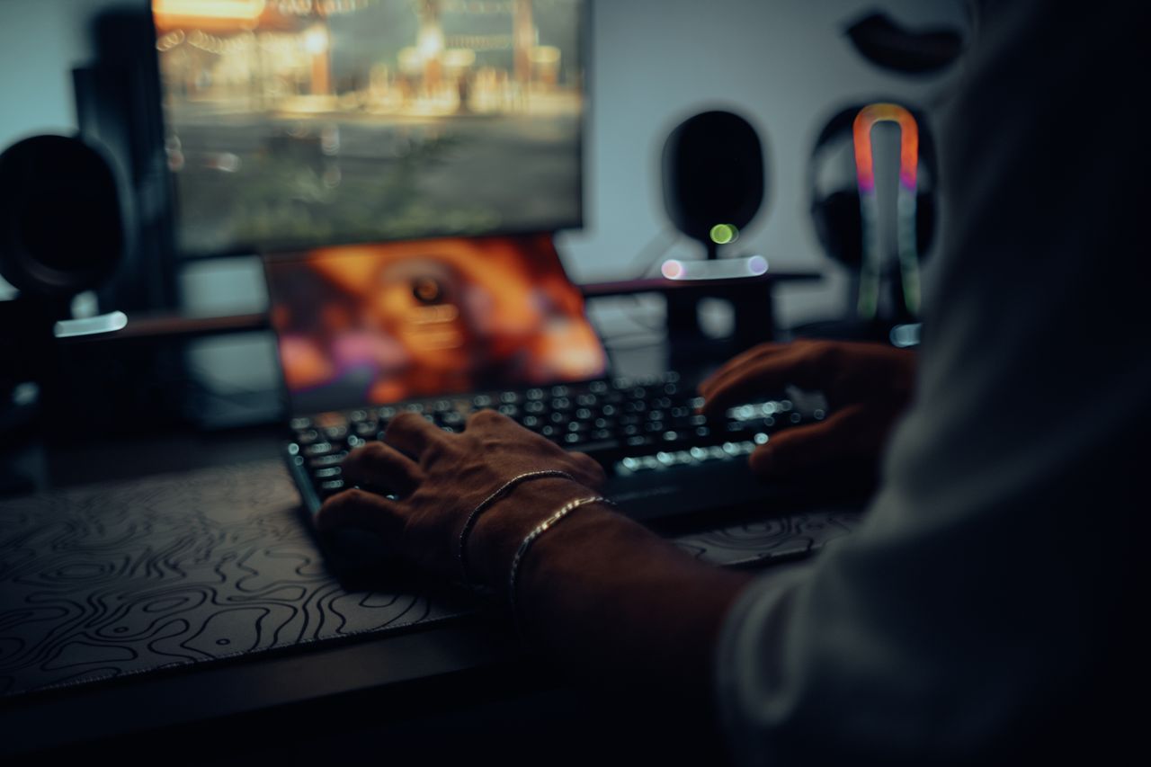 about-me-01 Focused man typing in a dimly lit room, creating a moody atmosphere.
